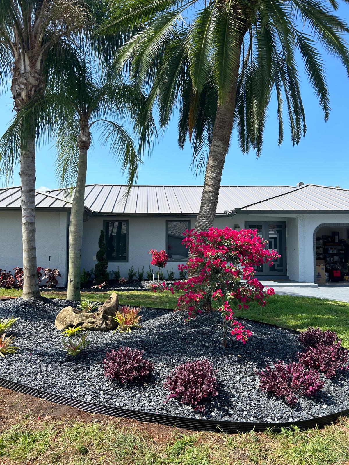 A charming home surrounded by lush palm trees and vibrant flowers in the foreground, creating a tropical atmosphere.